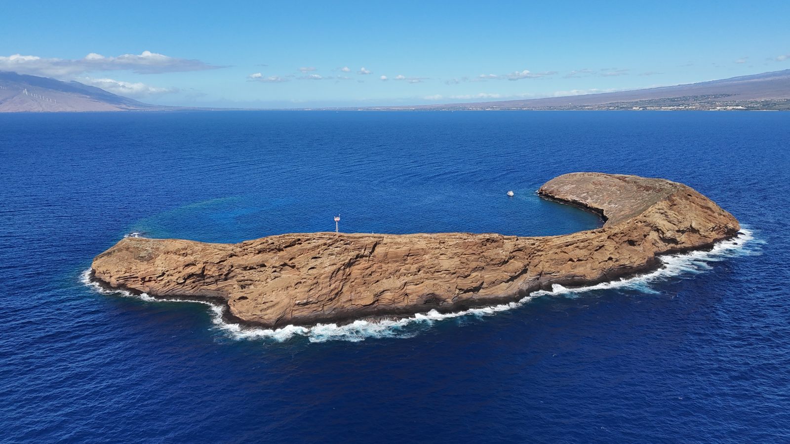 Aerial view of the crescent-shaped Molokini crater in deep blue water